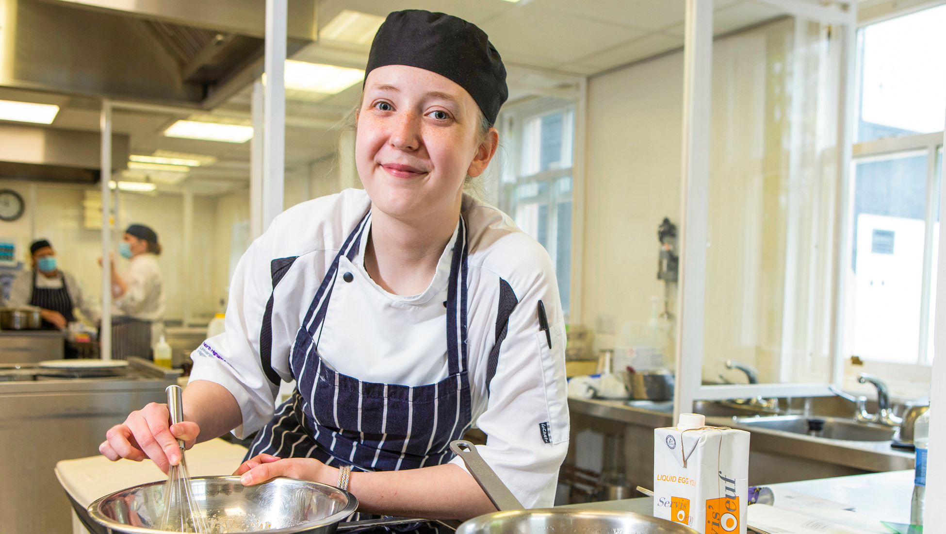 Cookery Student stirring whilst looking at camera