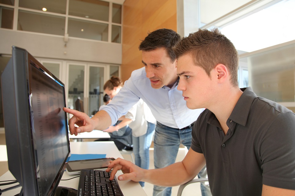 Man showing student or apprentice detail on computer screen