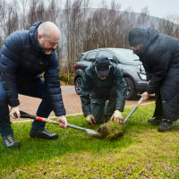 Lydia Rohmer and two others digging a hole in grass area with spades for tree planting