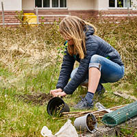 Lecturer kneeling down on the ground planting a tree