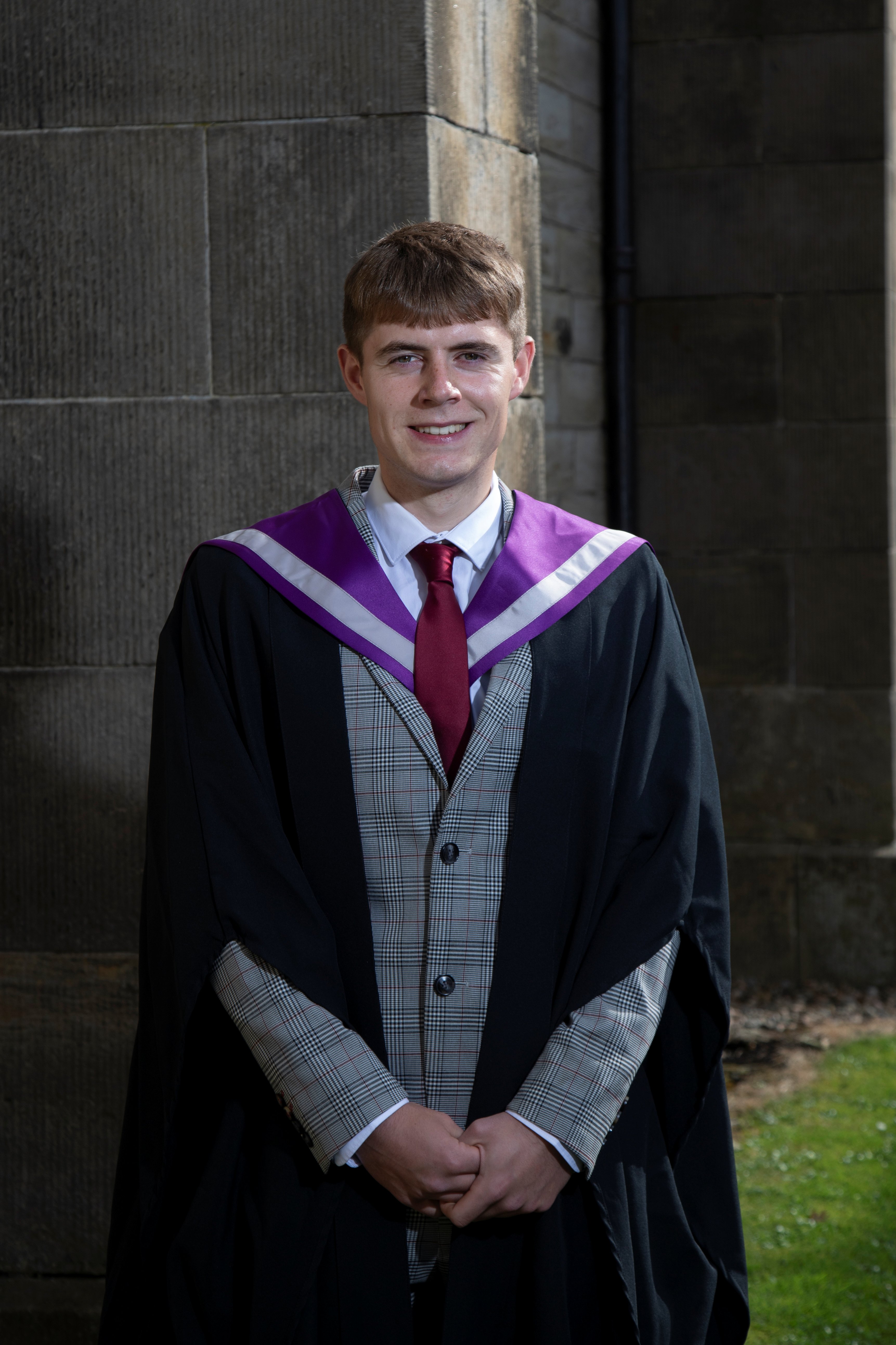 Image of Taylor Kerr in graduation gown at the Thurso graduation ceremony outside St Peters and St Andrews Church.