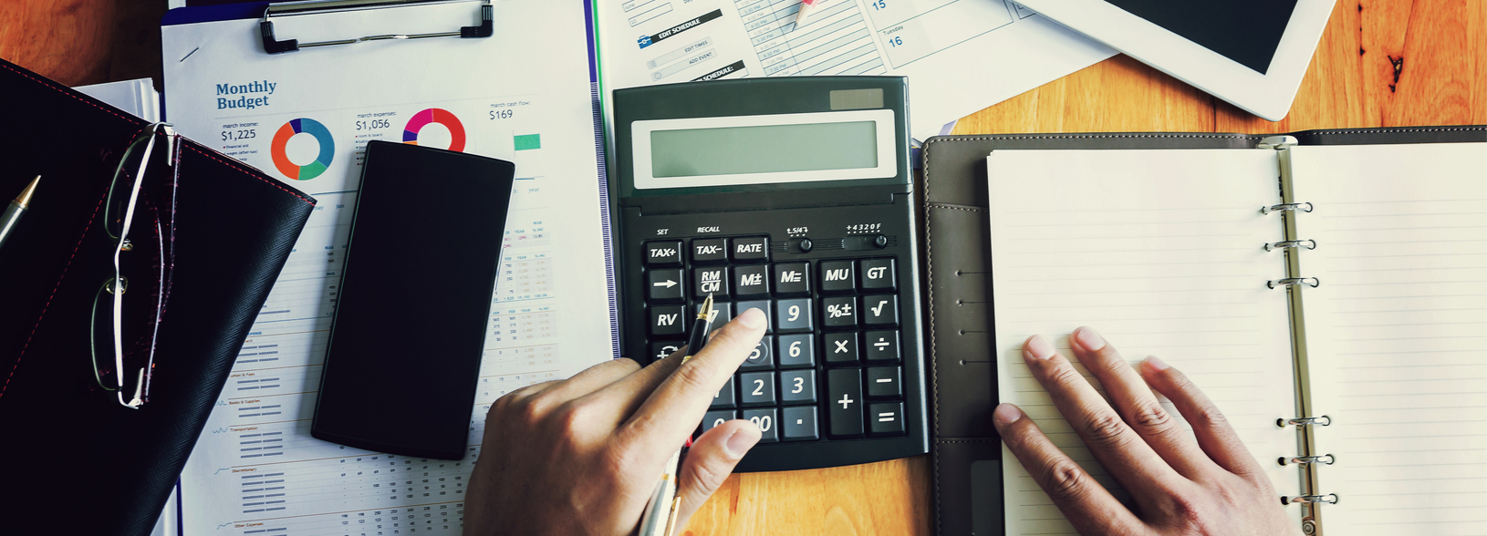 Image of desk with calculator, pens, and business paperwork